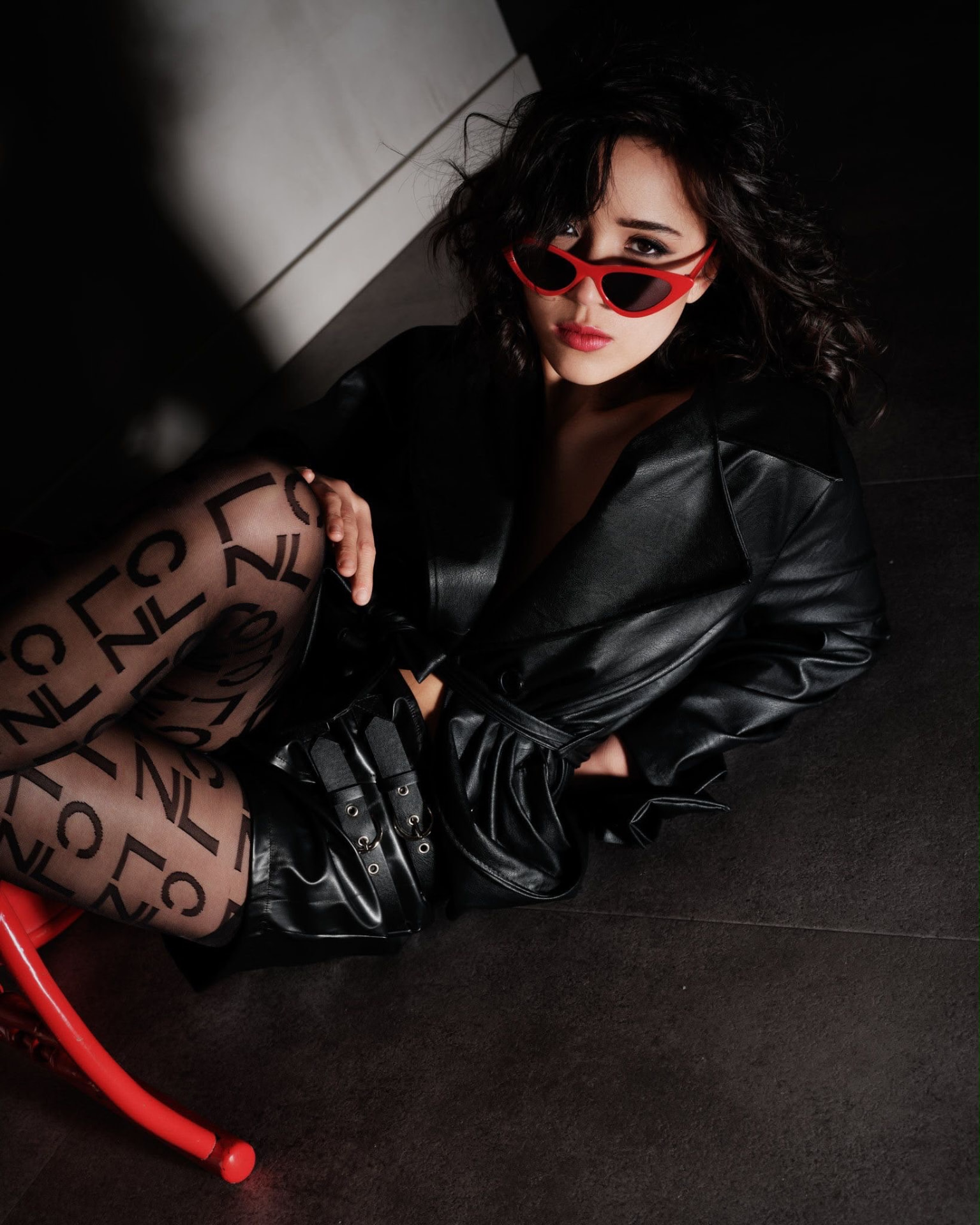 Victoria Amerson in a black leather coat and red cat-eye sunglasses